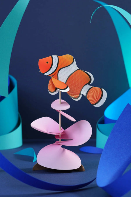 Colorful paper clownfish craft made by Assembli, featuring vibrant orange and white paper with detailed fins and expressive eyes.