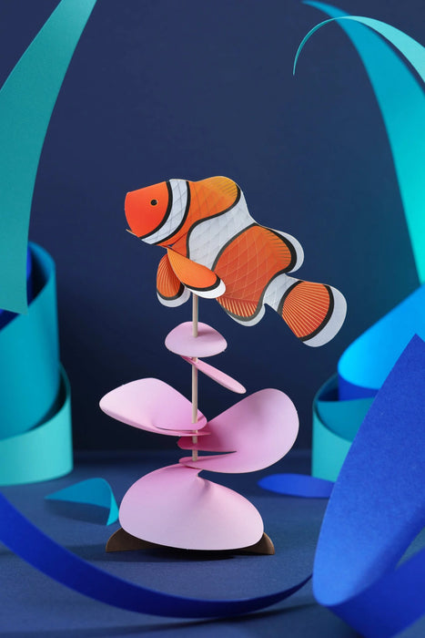 Colorful paper clownfish craft made by Assembli, featuring vibrant orange and white paper with detailed fins and expressive eyes.