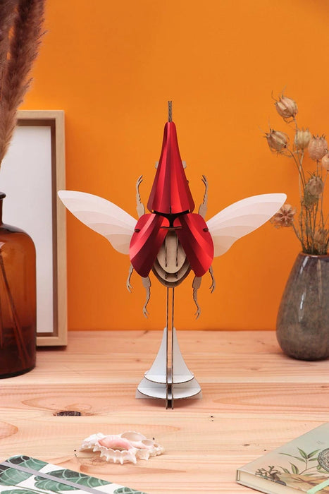 Assembli Paper Hercules Beetle craft kit featuring a large, red, translucent beetle with detailed wings and body for creative projects.