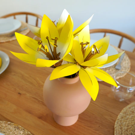 Yellow paper flowers craft by Assembli, showcasing colorful handmade paper floral decorations on a square background.