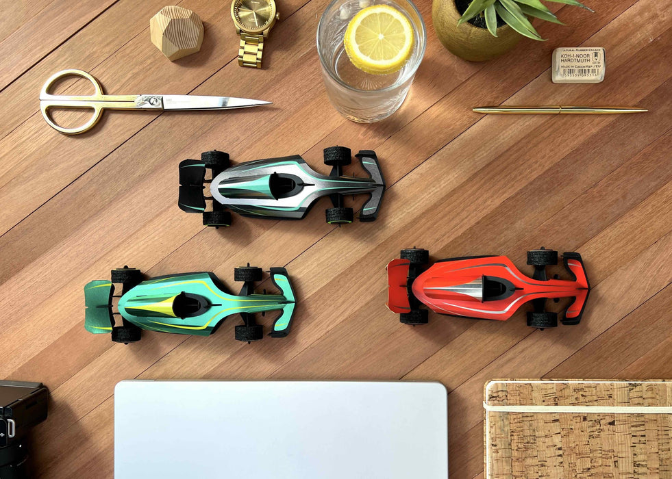 Assembli paper race car craft on a desk, featuring colorful paper components and a sleek racing design for creative projects.