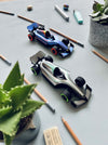 Assembli paper race car craft on a desk with a curved race track, showcasing a colorful folded paper vehicle for creative play.