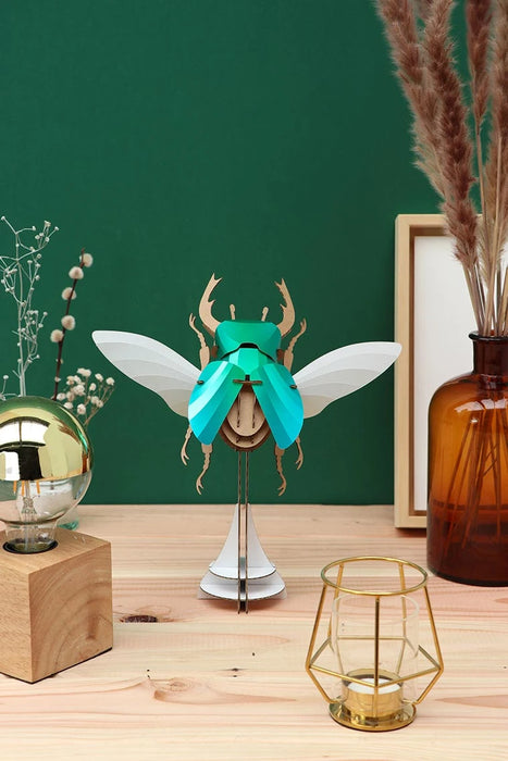 Large paper stag beetle craft by Assembli, showcasing detailed brown paper legs, antennae, and textured body on a transparent stand.