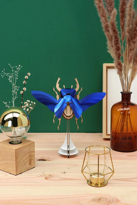 Large blue paper stag beetle craft by Assembli, featuring detailed paper wings and body, ideal for DIY craft projects.