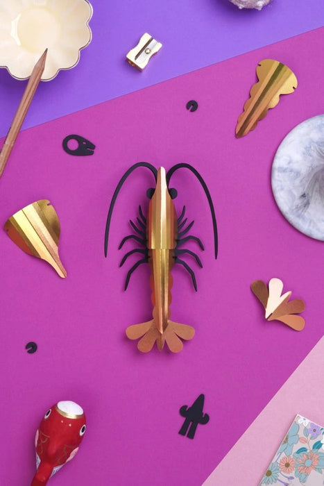 Yellow paper shrimp craft by Assembli, shown from a top-down view, featuring detailed paper textures and intricate design.