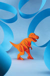 Orange paper T-Rex craft by Assembli, showcasing a detailed mini Tyrannosaurus dinosaur model for creative projects.