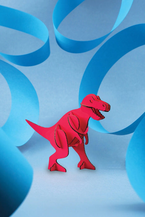 Pink paper T-Rex craft by Assembli, featuring a detailed miniature T-Rex figure made from folded paper.