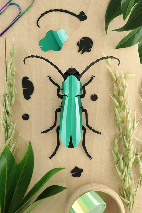 Green Paper Rosalia Beetle craft by Assembli, showcasing detailed, folded paper wings and body on a neutral background.