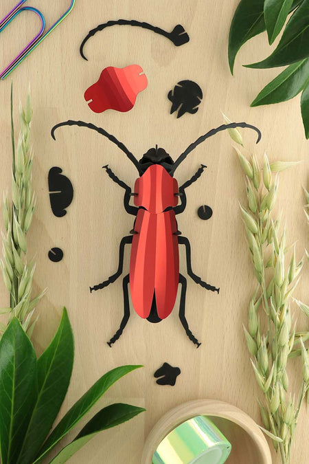 Red paper Rosalia beetle craft by Assembli, showcasing detailed handcrafted insect with vibrant red paper wings and body.