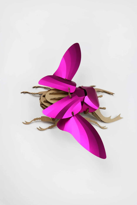 Large pink paper stag beetle craft from Assembli, featuring detailed wings and mandibles, on a white background.