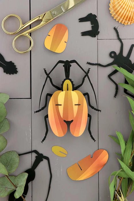 Yellow paper violin craft by Assembli, showcasing a detailed handmade paper model of a violin beetle.