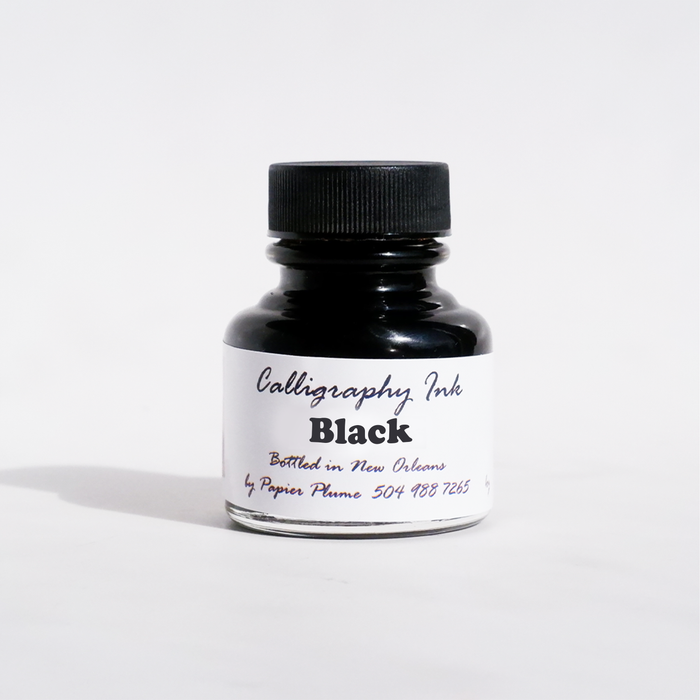 Black bottled calligraphy ink by Papier Plume, showing a glass bottle with ink and calligraphy pen on a white background.
