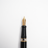 Aurora Optima black fountain pen with gold trim, showcasing a sleek design and elegant nib on a white background.