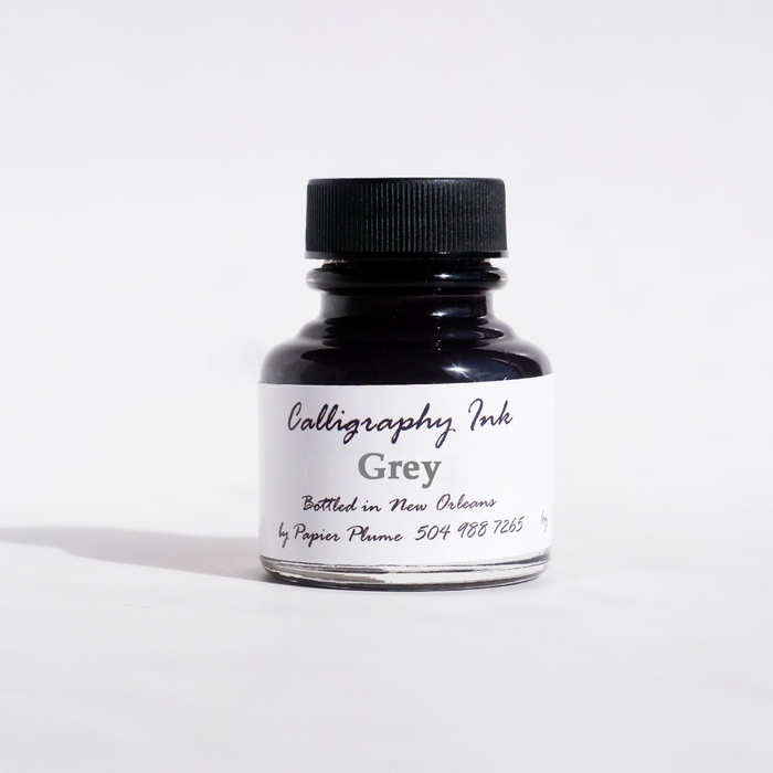 Papier Plume bottled calligraphy ink in grey with a glass bottle and black cap, ideal for artistic lettering and writing projects.