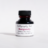 Bottled Burgundy calligraphy ink by Papier Plume showing a glass ink bottle with burgundy ink for artistic writing and calligraphy.