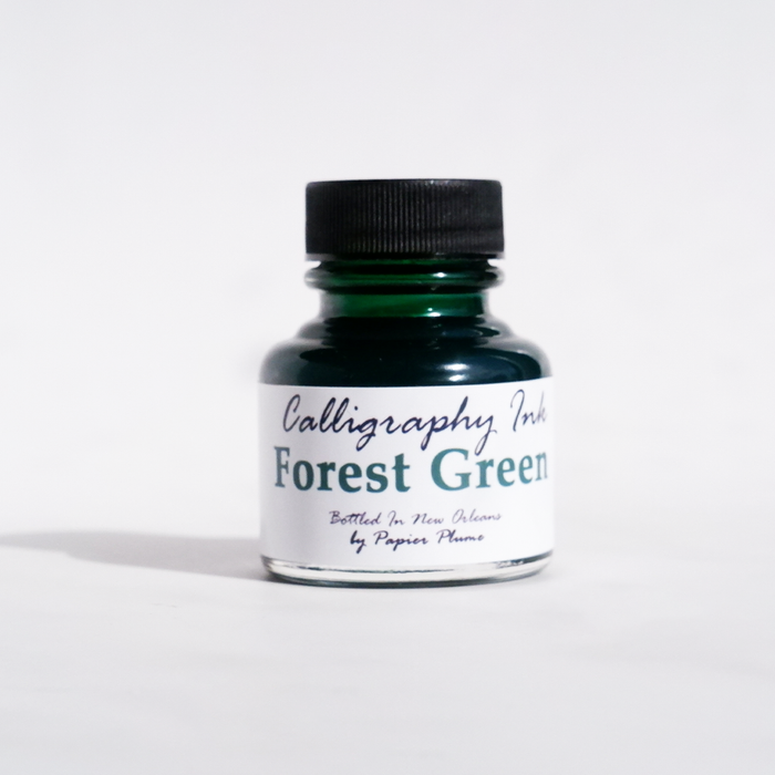 Bottle of Papier Plume calligraphy ink in forest green with a black cap, showcasing smooth ink flow and vibrant color.