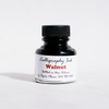 Bottle of Papier Plume Walnut Calligraphy Ink showing the dark brown ink inside a clear glass bottle.