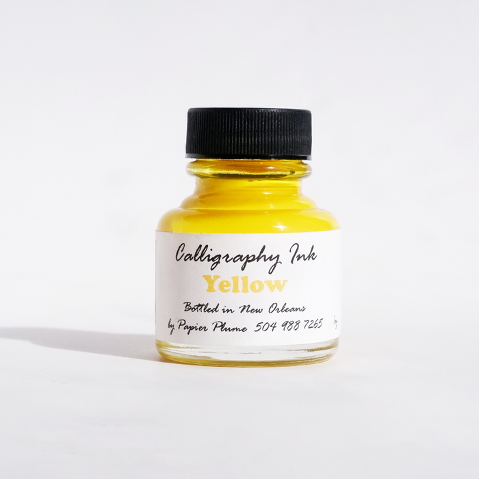 Yellow bottled calligraphy ink from Papier Plume, showcasing smooth, vibrant ink ideal for elegant calligraphy writing.