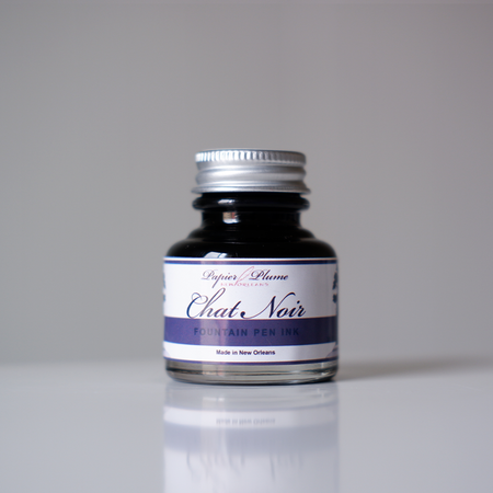 Black fountain pen ink bottle from Papier Plume's Chat Noir collection, featuring elegant ink in a glass container