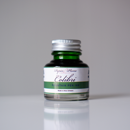 Papier Plume Colibri fountain pen ink bottle with vibrant ink inside, designed for smooth writing and elegant calligraphy.