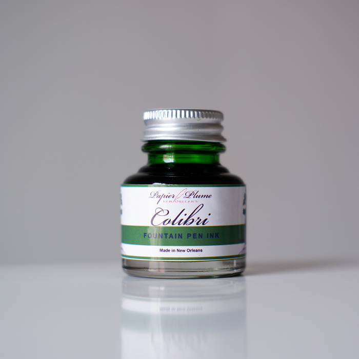 Papier Plume Colibri fountain pen ink bottle with vibrant ink inside, designed for smooth writing and elegant calligraphy.