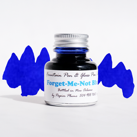 Papier Plume Forget-Me-Not Blue fountain pen ink in glass bottle with ink swatch, vibrant blue color for elegant writing.
