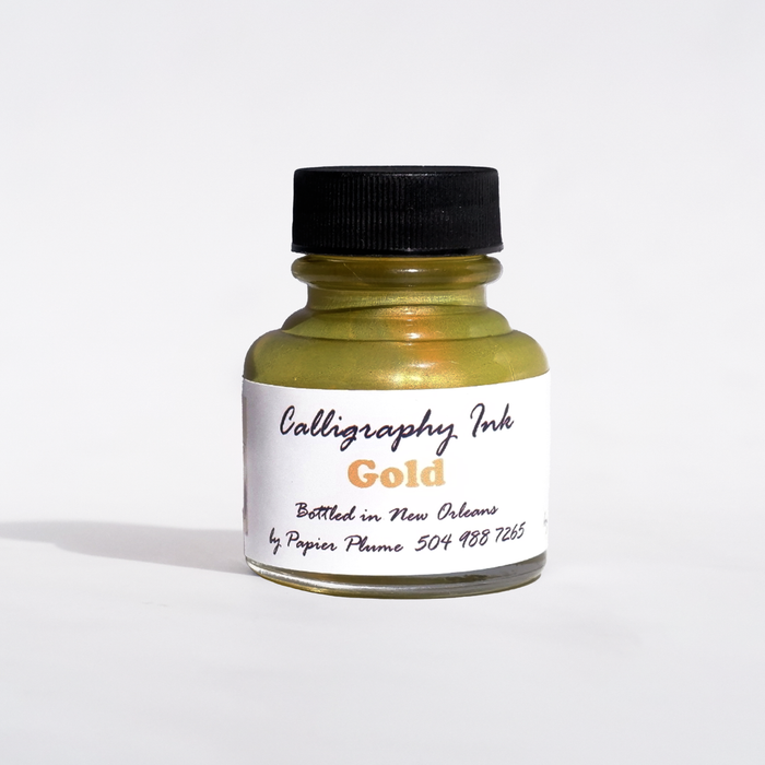 Gold metallic calligraphy ink in a glass bottle from Papier Plume, showcasing luxurious ink with a shiny, metallic finish.