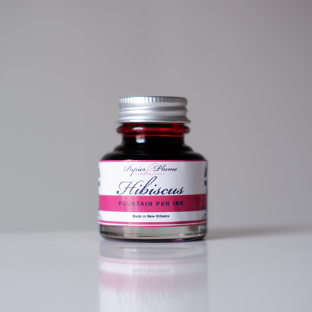Papier Plume fountain pen ink in Hibiscus color, vibrant red-pink ink in a glass bottle with a black cap.