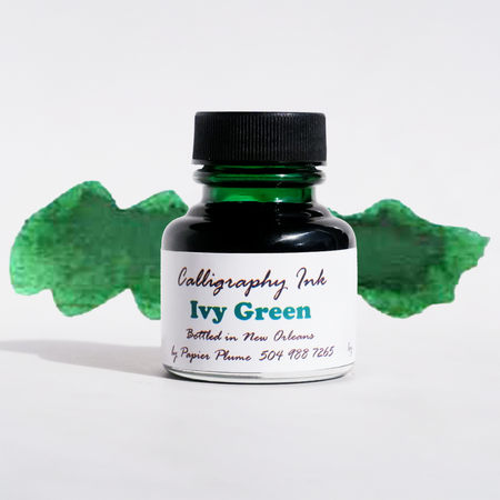 Bottle of Papier Plume Ivy Green calligraphy ink with a glass ink bottle and green ink inside.