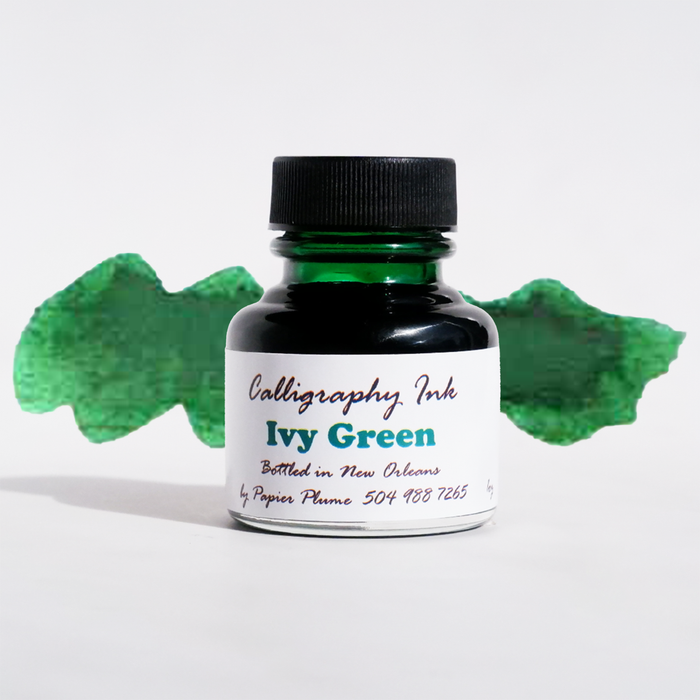 Bottle of Papier Plume Ivy Green calligraphy ink with a glass ink bottle and green ink inside.