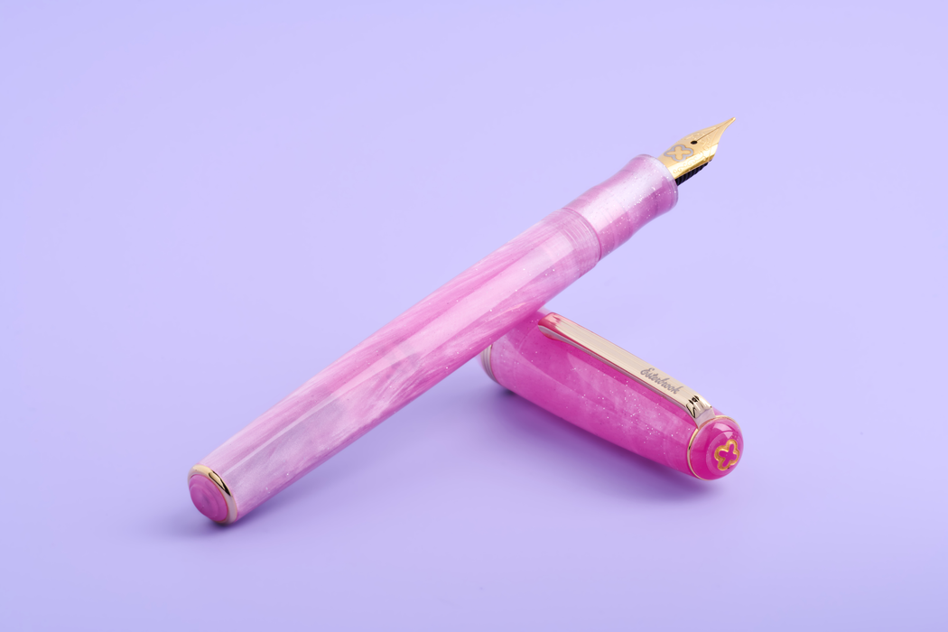 Esterbrook Love Potion Jr fountain pen with pink barrel and gold accents, showcasing its elegant design.
