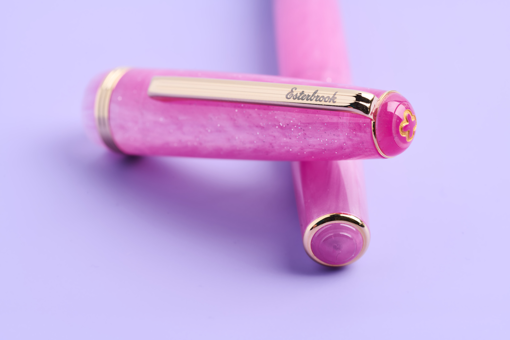 Esterbrook Love Potion Jr fountain pen with pink barrel and gold accents, showcasing its elegant design and smooth writing tip.