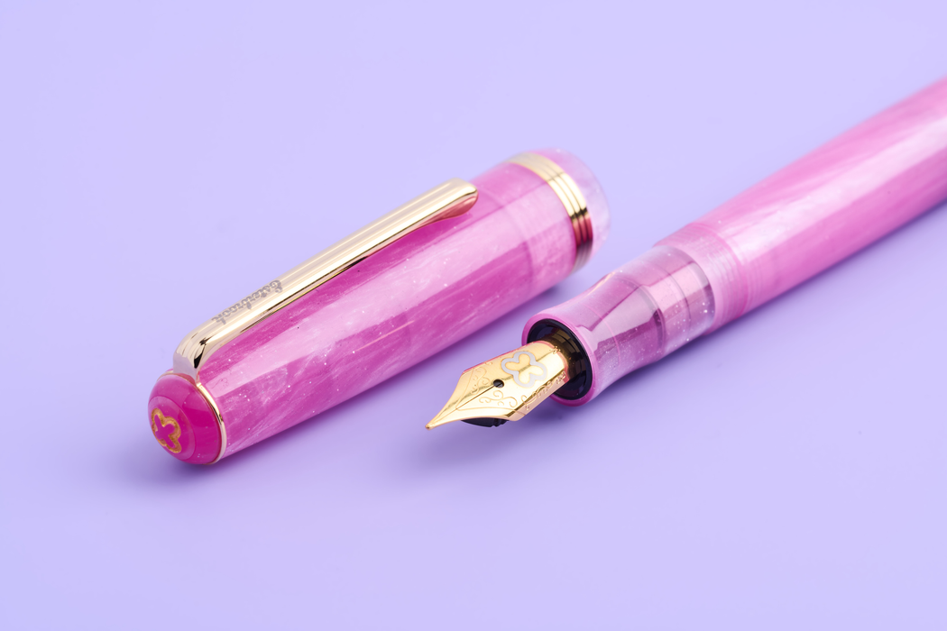 Esterbrook Love Potion Jr fountain pen with pink barrel and gold accents, showcasing its elegant design and smooth writing nib.
