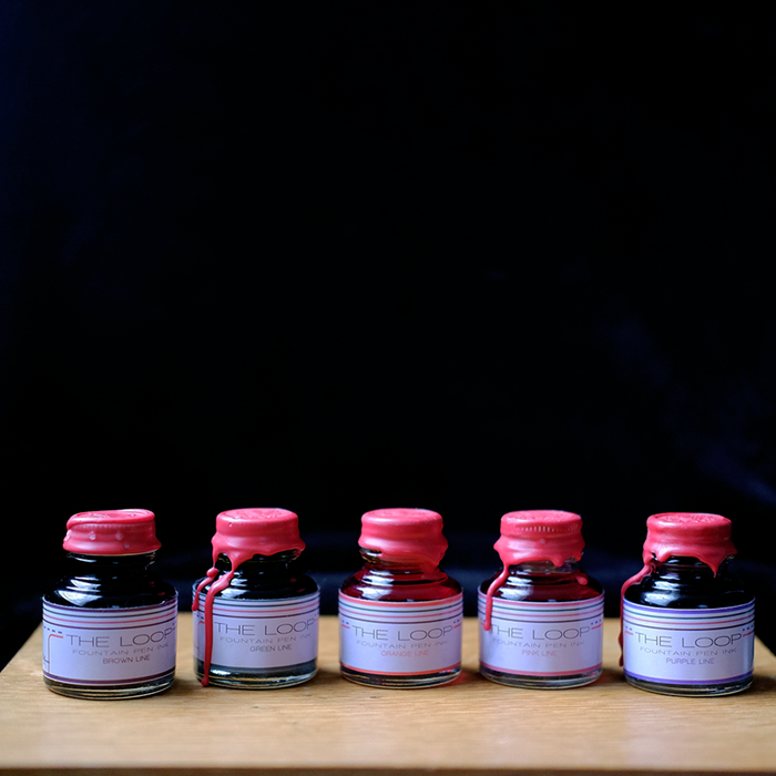 Papier Plume Loop Series fountain pen ink bottle with vibrant blue ink inside, showcasing elegant packaging and labeling.