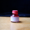 Papier Plume The Loop Series fountain pen ink bottle in vibrant orange color, showcasing the ink and elegant packaging.