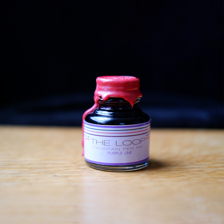 Papier Plume Loop Series fountain pen ink in a purple ink bottle, showcasing the vibrant ink inside and the elegant packaging.