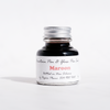 Papier Plume maroon fountain pen ink bottle with ink swatch and label showing product name and brand.