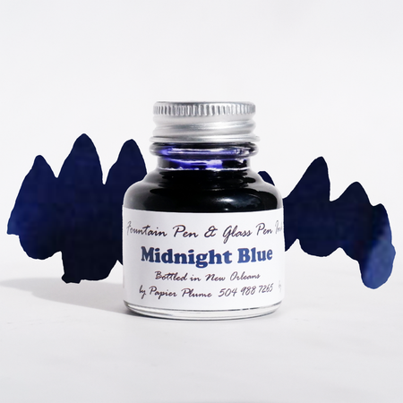 Bottle of Papier Plume Midnight Blue fountain pen ink with a clear glass container and dark blue ink visible inside.