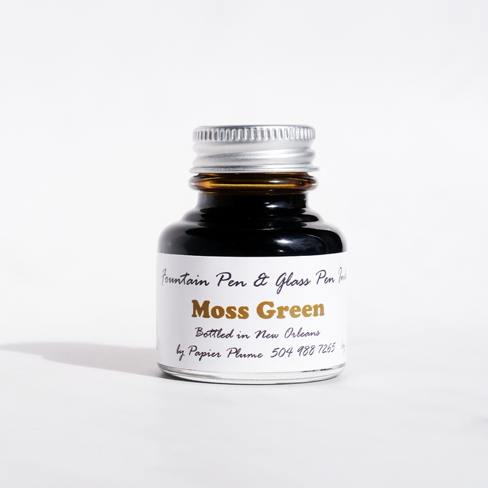 Papier Plume moss green fountain pen ink in a glass bottle, showcasing rich green ink for writing and artistic use.