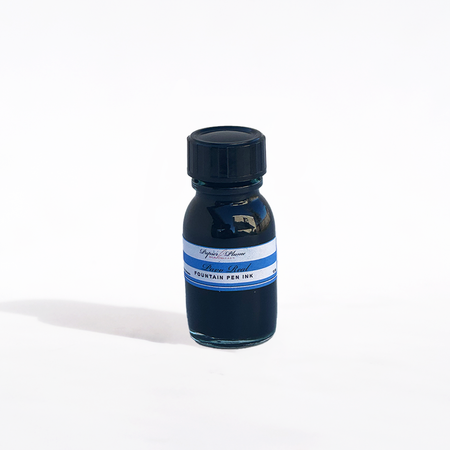 Papier Plume Pavo Real fountain pen ink in a glass bottle with vibrant blue and green ink inside.