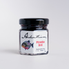 Anderillium Piranha Red fountain pen ink in a glass bottle with vibrant red ink visible inside.