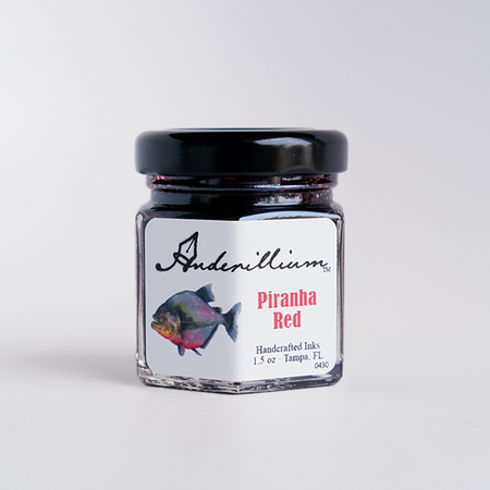 Anderillium Piranha Red fountain pen ink in a glass bottle with vibrant red ink visible inside.