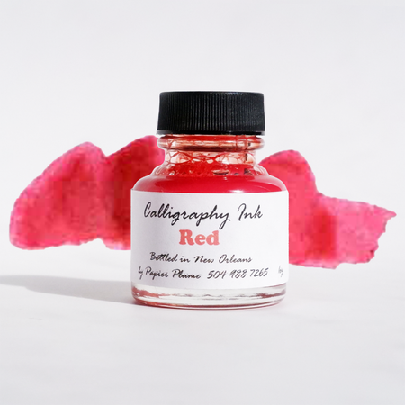 Bottle of Papier Plume red calligraphy ink with a clear glass container and black screw cap on a white background.