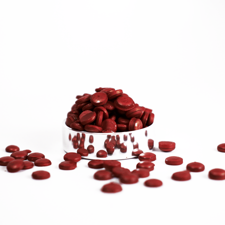 Raspberry wax beads by Papier Plume in a small bowl, ready for wax melting and hair removal.