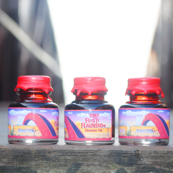 Papier Plume Rusty Rainbow shimmer fountain pen ink bottle with vibrant, multicolored ink inside.
