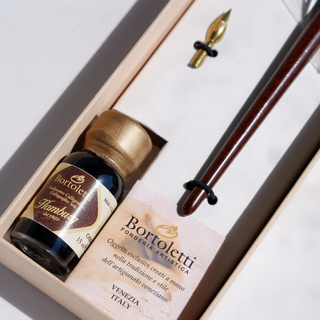 Bortoletti wood and bronze dip calligraphy pen set with nibs and ink bottle on a wooden surface.