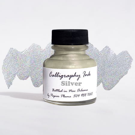 Bottled metallic silver calligraphy ink from Papier Plume, showcasing the shiny ink inside a clear glass bottle with a black cap.