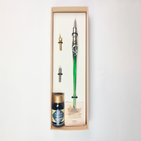 Set of 20 green Bortoletti glass dipping pens arranged on a white surface with ink bottles and paper.