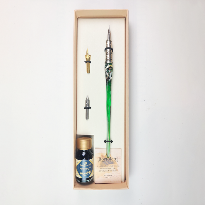 Set of 20 green Bortoletti glass dipping pens arranged on a white surface with ink bottles and paper.