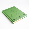A Chronicle Books Studio Ghibli My Neighbor Totoro journal with a colorful cover featuring Totoro and forest scene.